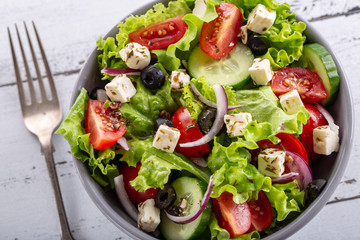 Fresh greek salad served in bowl with fork.