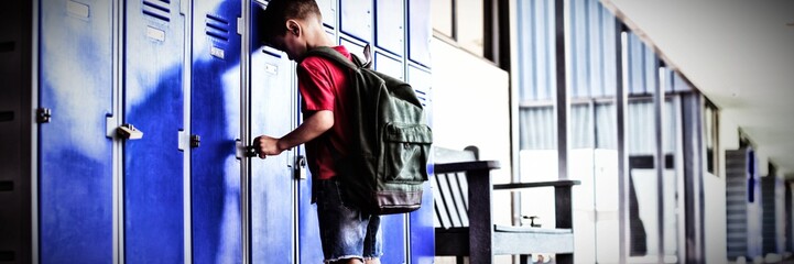 Full length of boy leaning on lockers in corridor