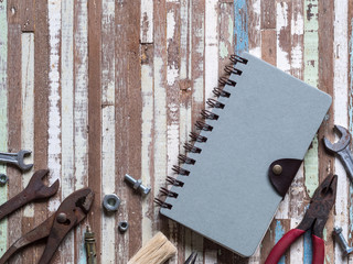 Blank space cover note book and old rusty handy working tools on gruge wooden background. Top view. Labor day concept with blank cover notebook for copy space.
