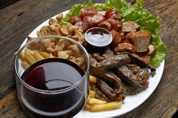 Snacks with fries, crackers, meat, pork, sausage, babercue sauce and glass of red wine