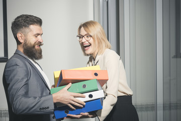 Businesswoman and businessman with folders. Man help woman to carry binders in office. Bearded man and sexy girl with documents. Office romance and flirt concept. Business cooperation and teamwork