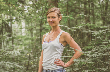 Smiling young woman in a white tank top in the forest