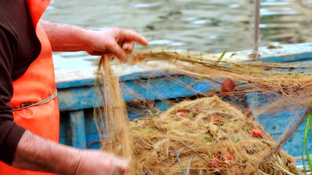 Fisherman cleans and prepares the net before going offshore to fish with the boat. Porticello (Palermo), Sicily, Italy.