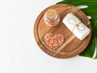 Beautiful pink Himalayan salt placed in heart shape and towel on wooden plank. Relaxation and spa concept.
