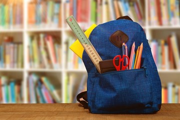 Composite image of bag with school supplies on wooden table - Powered by Adobe