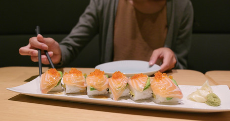 Woman eating sushi in restaurant