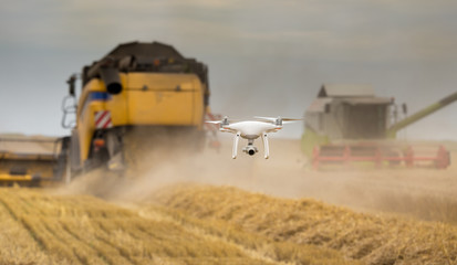 Drone flying in front of combine harvester - obrazy, fototapety, plakaty