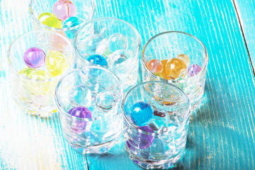 six glasses for vodka filled with colorful rubber balls