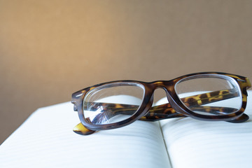 close up vintage glasses on blurred opened book with copy space