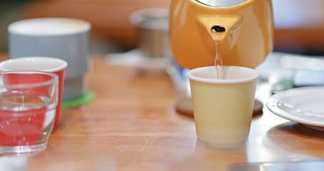 Pouring tea from teapot in coffee shop