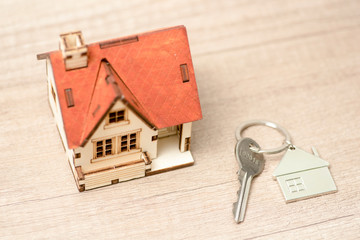 Closeup of house model and keys on wooden table