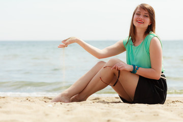 Fototapeta na wymiar Happy woman sitting on beach near sea
