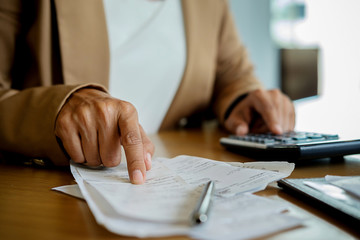 Woman with bills and calculator. Woman using calculator to calculate bills at the table in office....