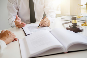 Justice and Law concept. Legal counsel presents to the client a signed contract with gavel and legal law or legal having team meeting at law firm in background