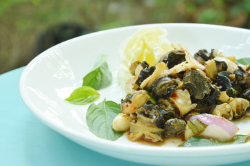 spicy golden apple snail with herb salad on white plate