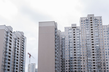 Naklejka premium New grey multi-storey residential buildings and construction crane.