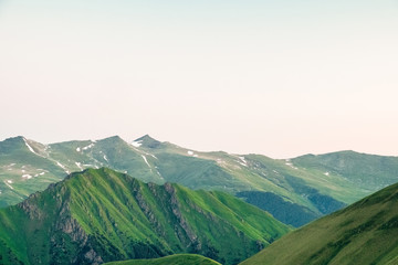 slopes of mountain ranges with rock formations and green grass landscape background image
