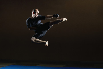 Fototapeta na wymiar Kicking in a jump in the performance of an athlete in black gloves