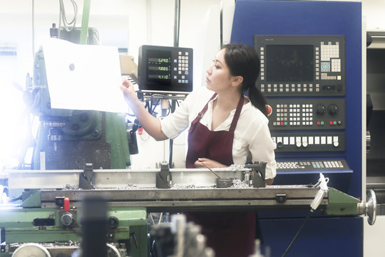 Female engineer looking at technical drawings in a workshop