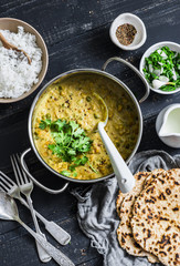 Indian dhal in  cooking pan with jasmine rice, coriander and whole grain flatbread on dark background, top view. Flat lay. Healthy vegetarian food
