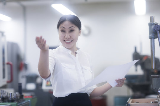 Smiling Female engineer holding a data sheet gesturing with her hand