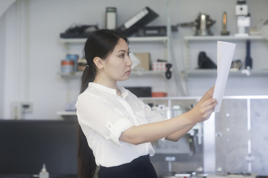 Female engineer standing in a workshop looking at technical drawings
