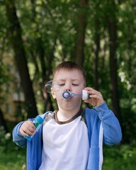 4 years Little boy with soap bubbles in summer green trees park, funny leisure time. Active kid playing in the garden on a sunny summer day, Out doors activities for children