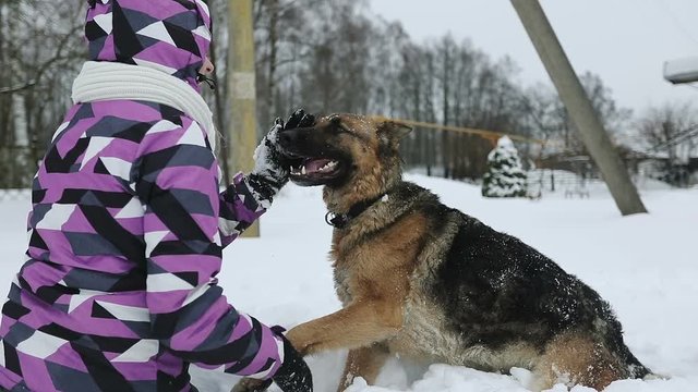 A young woman in a winter jacket stroking the dog's snout.