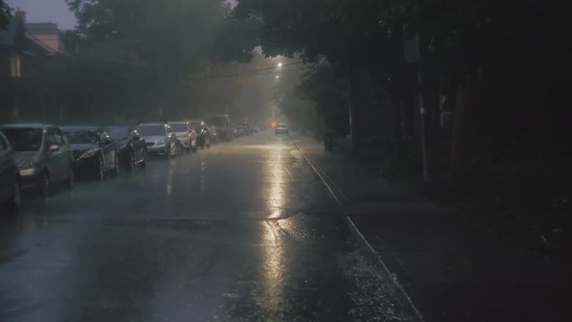 Establishing shot of a residential city street at night during an electrical storm. Cinematic 4K footage. Slow motion.