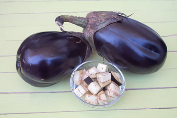 eggplants in cubes on a green wooden table viewed from close up