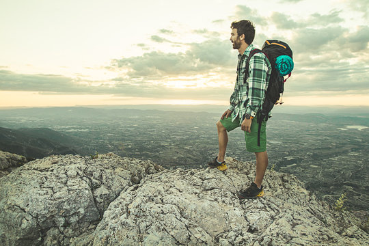 Mountaineer on top of a mountain with a backpack. Guy practicing trekking