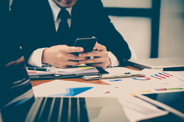 A businessman analyzing investment charts at workplace and using laptop and touch tablet.