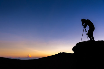 Silhouette Young Man With Tripod Taking A Photo On The Top of Mount Agung Volcano at Sunrise. Bali, Indonesia