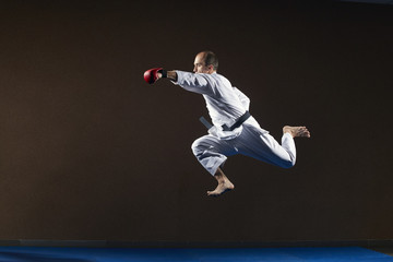 An athlete with red overlays on his hands beats a blow with his hand in a jump