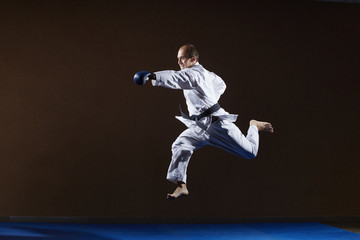 Fototapeta na wymiar In karategi, an adult athlete trains punch hand in jump