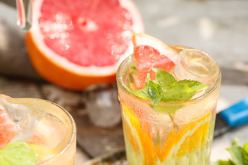 citrus lemonade in glass jug with mint. Orange. Grapefruit and lemon. On greenery background.