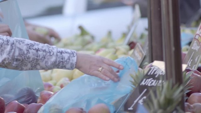Slow Motion Shot Of Male And Female Customers Hands Choosing Green Apples And Bagging Them Into Blue Plastic Bags At A Street Fruit Market Stall, Supplying Plastic Carrying Bags To Customers.