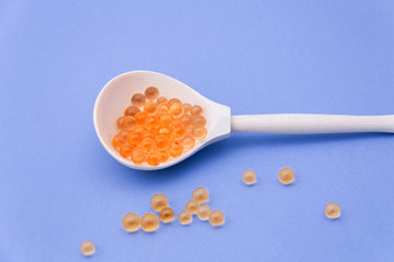 A wooden spoon with red caviar on a blue background.