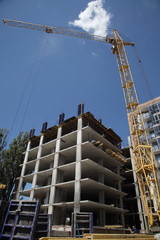 A modern new building. Working crane on the construction of the house. Construction site with cranes on sky background