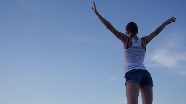 A slender attractive girl raised her arms up, waved them, she felt freedom, against the blue sky. HD, 1920x1080, slow motion.