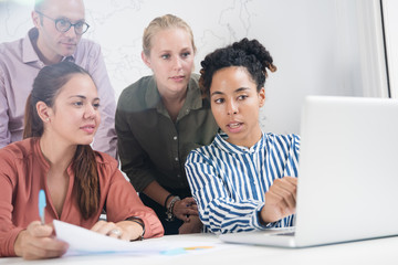 Fototapeta premium Business team gathered around a laptop discussing