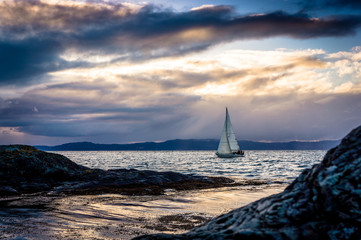 Sailboat among the rocks against the background of a spectacular sunset.