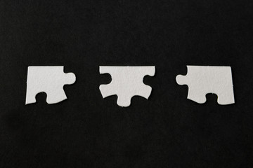 White jigsaw puzzle pieces on black background; 