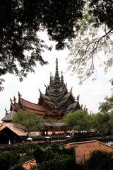Fototapeta premium The modern construction of the temple of truth in Thailand against the background of green trees