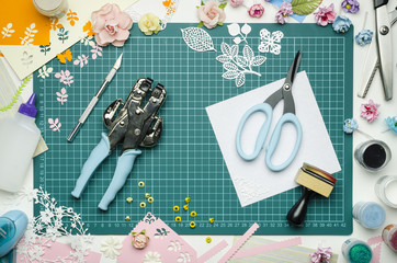 Multi-colored paper crafts on the cutting mat and scrapbooking tools, top view