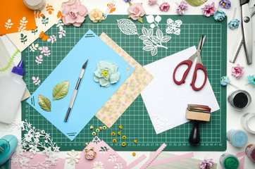 Multi-colored paper cards on the cutting mat, tools and materials for scrapbooking, top view