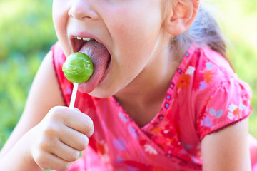  The little girl licks the lollipop.