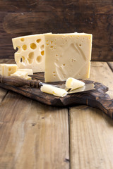 Cheese with holes large and small. Wooden board and knife. Traditional Dutch cheese. Copy space