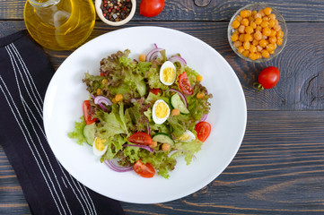 Light summer salad with fresh vegetables, greens, quail eggs and chickpeas. Vegetarian dish. Proper nutrition. Top view.