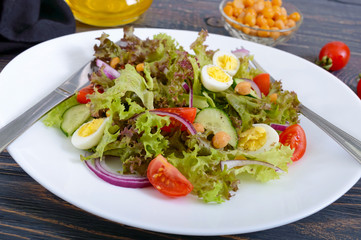 Light summer salad with fresh vegetables, greens, quail eggs and chickpeas. Vegetarian dish. Proper nutrition. Close-up.